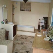 DESPUÉS: Cuarto de baño final con azulejos moriscos de estilo antiguo recién instalados en el piso y estuco a base de cal en las paredes. Yasmin baño después